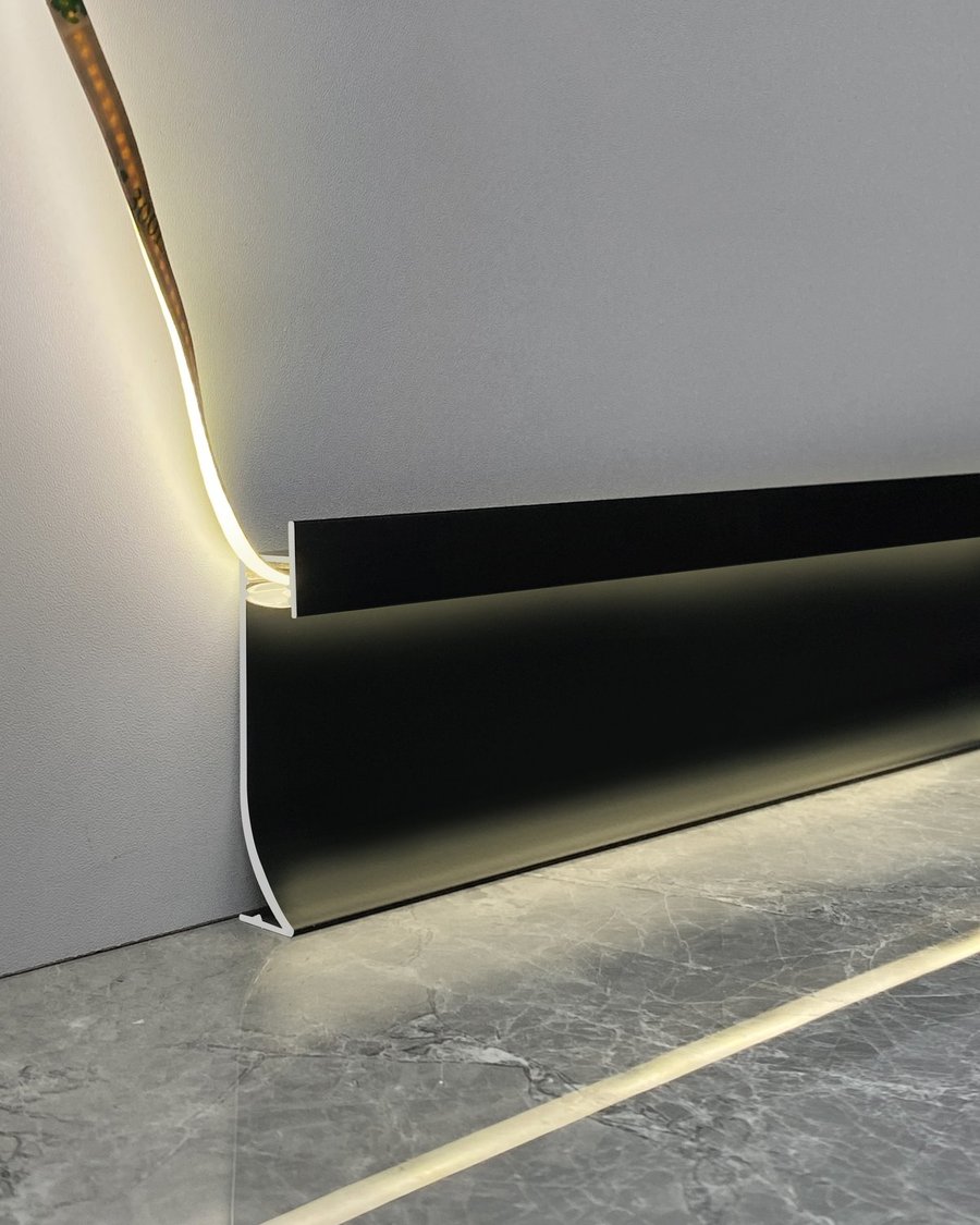 A black recessed LED baseboard lit along a marble wall